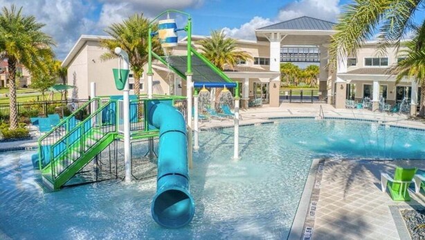 A water park area with a pool, slides, and a building with a covered patio. - 2616 Tranquility, Kissimmee, 6 BED (Kissimmee)