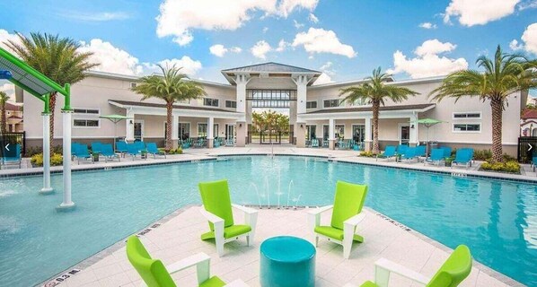 A pool area with a central fountain, surrounded by lounge chairs and palm trees. - 2458rd · Brand New 12br Disney Mansion/pool/spa/game Room (Kissimmee)
