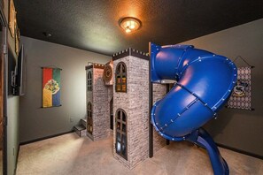 A play area with a blue slide and a brick playhouse. - 2458rd · Brand New 12br Disney Mansion/pool/spa/game Room (Kissimmee)