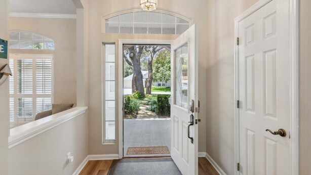 A hallway with a white door, a small window, and a doorbell. - 2888 Tidewater Drive (Fernandina Beach)