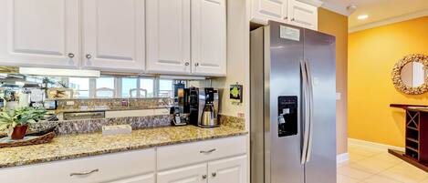 A kitchen with white cabinets, a stainless steel refrigerator, and a granite countertop.
