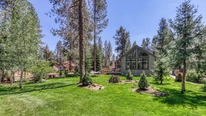 A modern house surrounded by a well-maintained lawn and tall pine trees. - 28 Big Leaf (Bend)