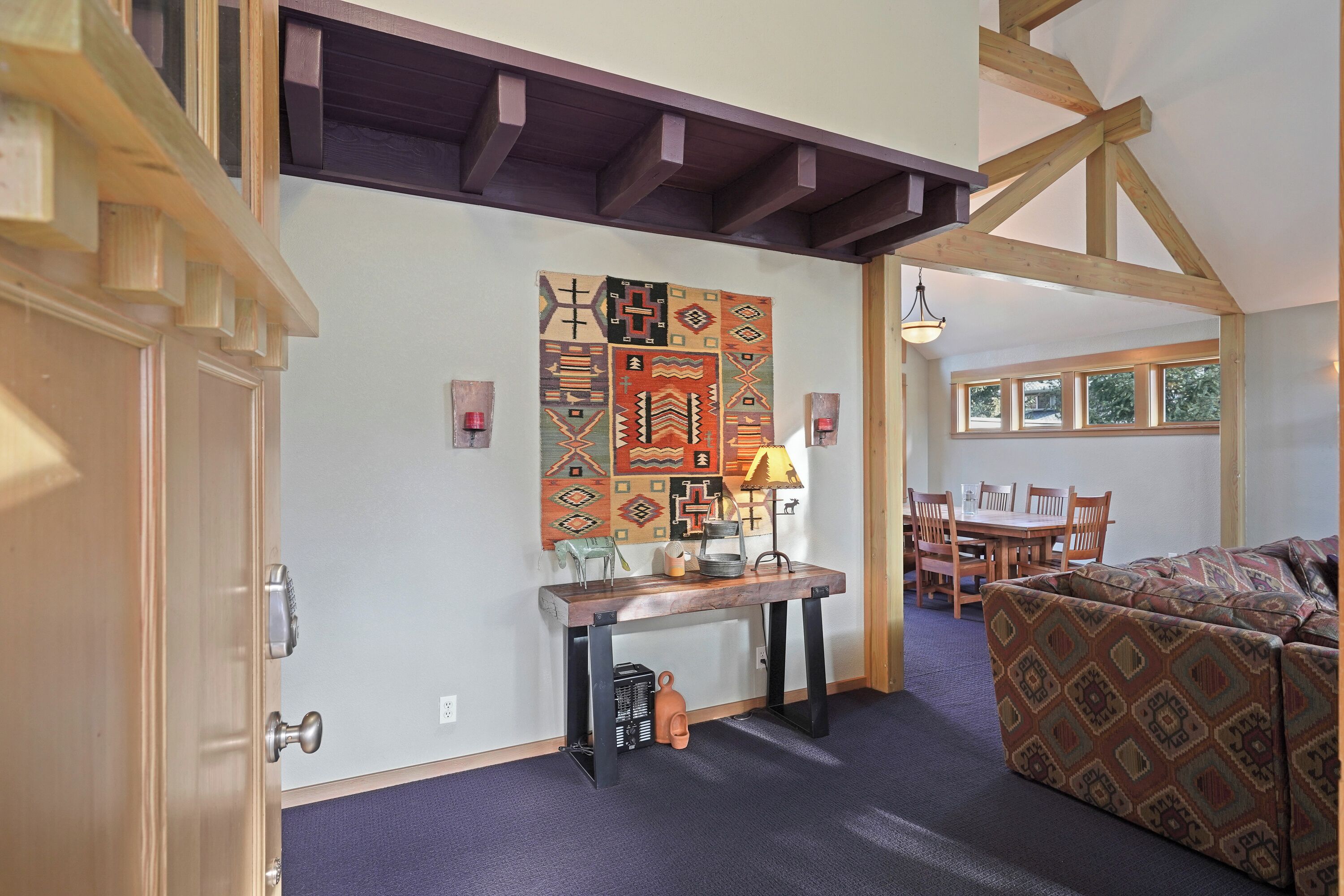A room with a wooden table, a patterned rug, and a couch.