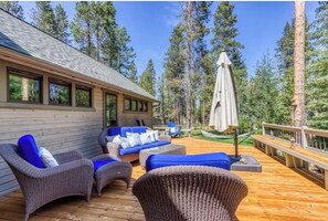 A wooden deck with outdoor furniture, including sofas and chairs, surrounded by tall trees. - 28 Big Leaf (Bend)