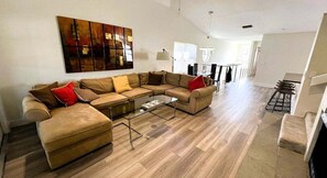 A living room with a sectional sofa, a coffee table, and a large abstract painting on the wall. - 2971 Cottage Grove Court Orlando, 3bed (Orlando)