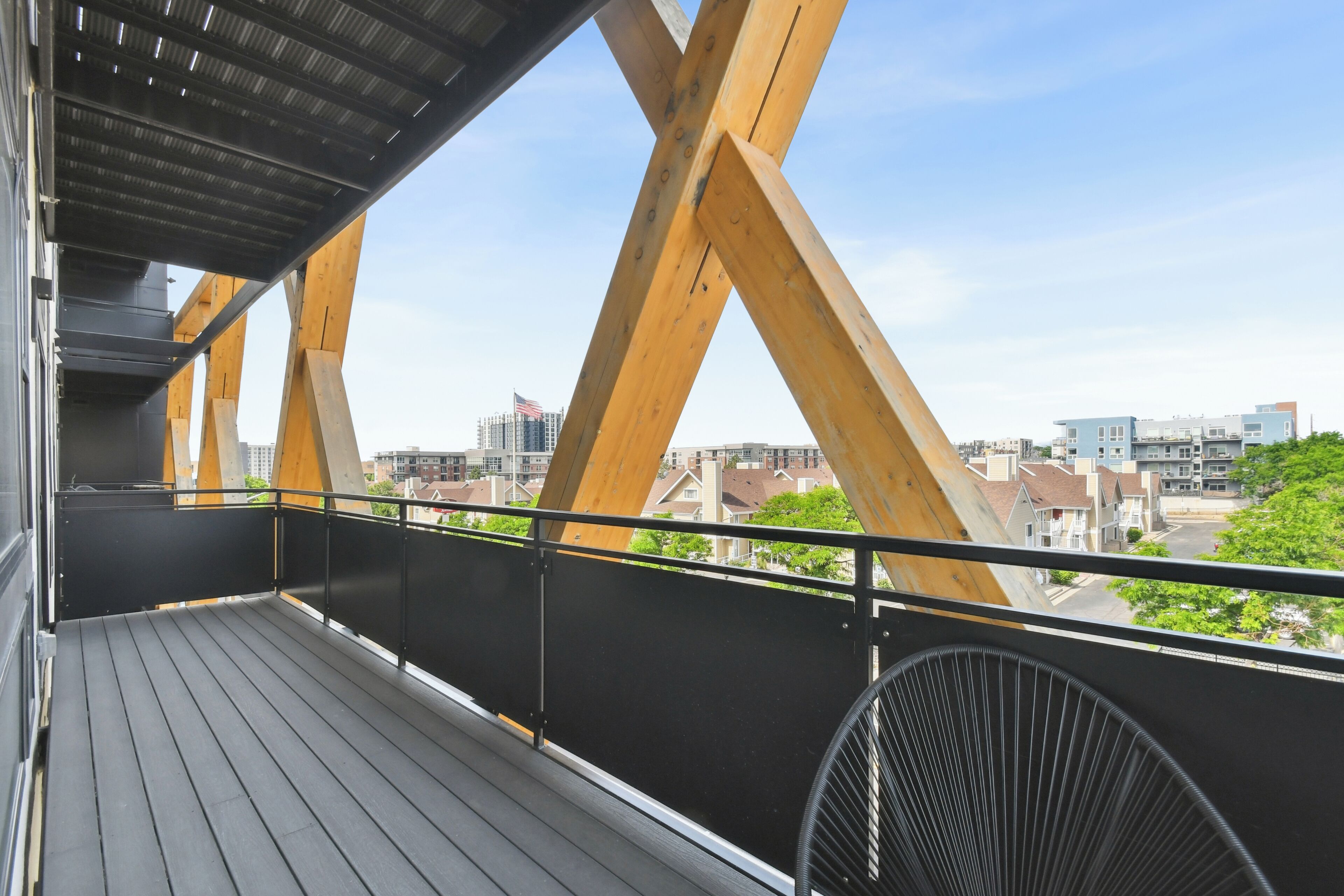 A balcony with a view of a cityscape, featuring a metal railing and a fan.