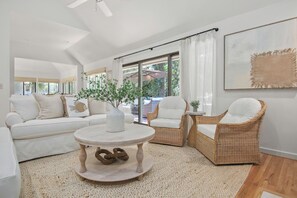 A spacious living room with a white sofa, two wicker chairs, a round coffee table, and a large window with curtains. - 2908 Captain Sams (Seabrook Island)