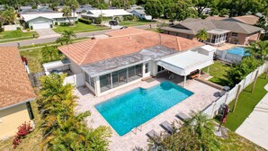 Una propiedad residencial con piscina, un patio cubierto y vistas a casas vecinas.