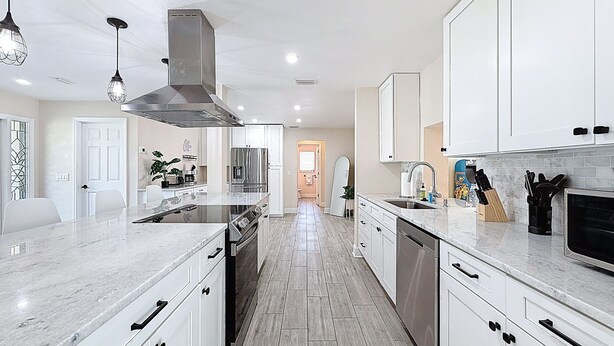 Una cocina moderna con armarios blancos, electrodomésticos de acero inoxidable y una isla central.