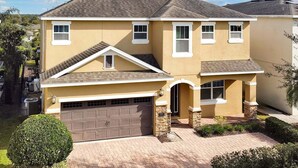 A two-story house with a garage, a covered entryway, and a well-maintained lawn. - 261 Lasso Drive 6bed (Kissimmee)