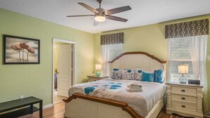 A bedroom with a bed, bedside tables, a ceiling fan, and a door. - 2820-5-rc-impeccable Corner lot Home (Kissimmee)
