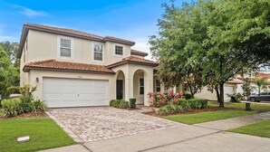 A two-story house with a garage, a tiled roof, and a well-maintained lawn. - 2820-5-rc-impeccable Corner lot Home (Kissimmee)