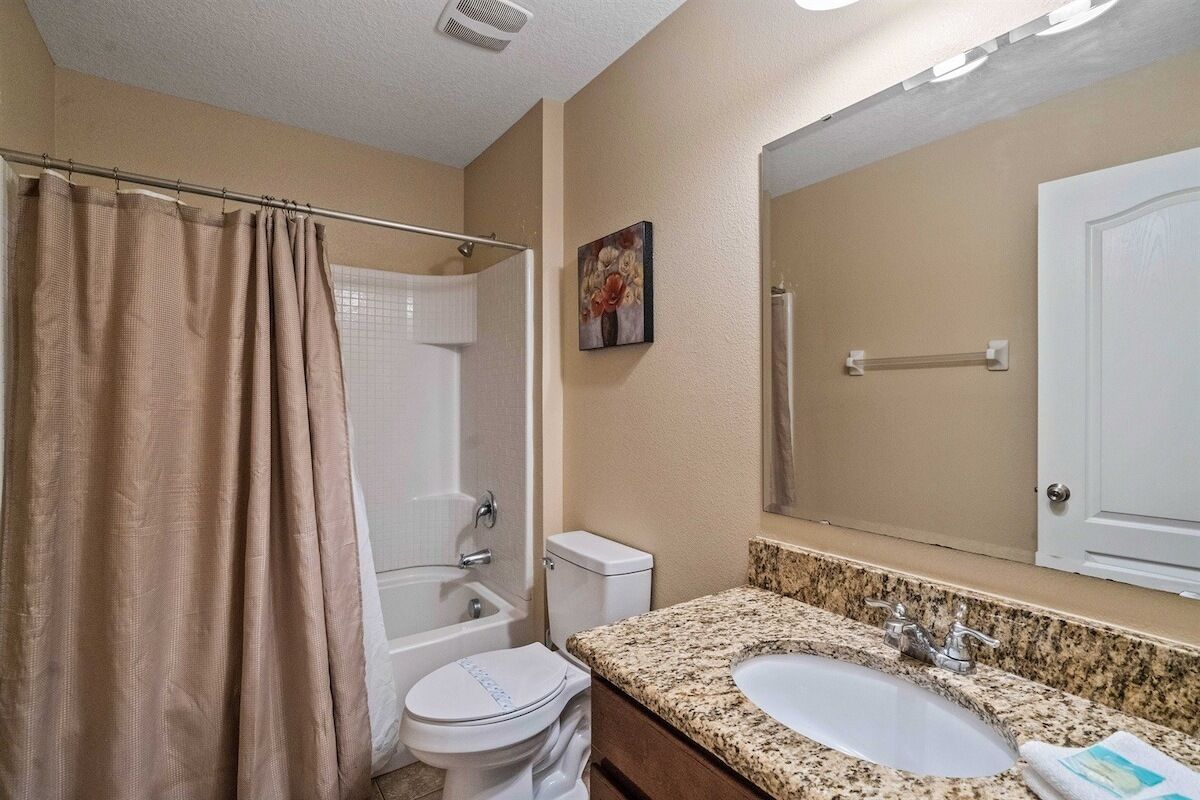 Un baño con ducha, inodoro, lavabo y un espejo grande.