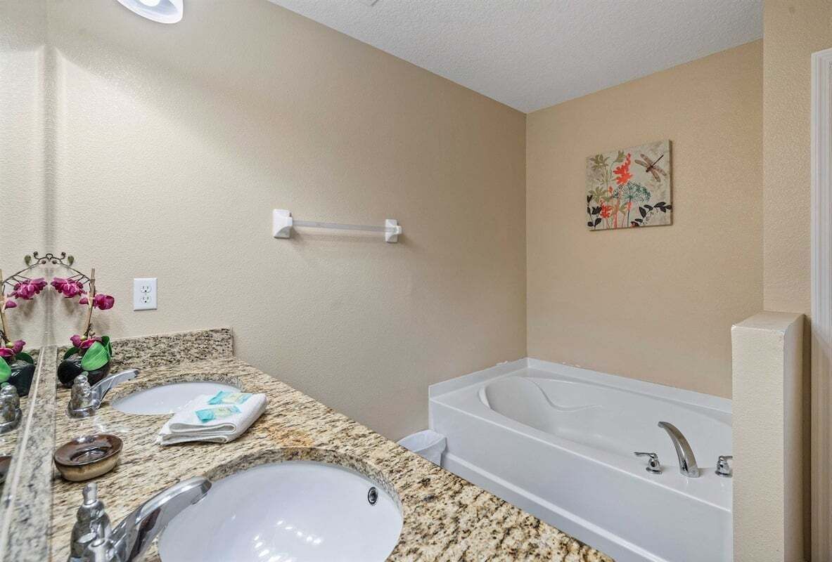 A bathroom with two sinks, a bathtub, and a towel rack.