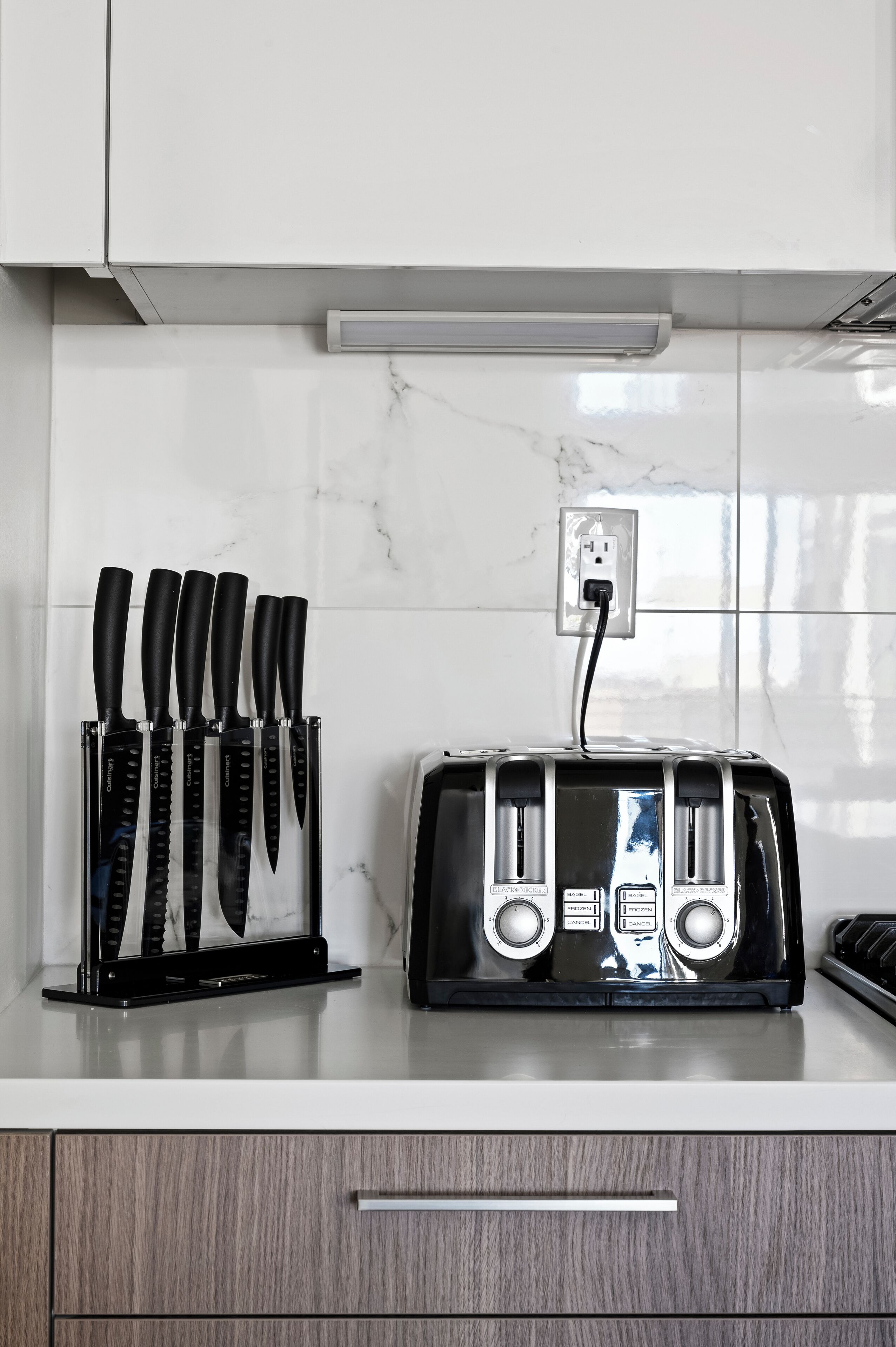 A kitchen with a marble backsplash, a knife block, and a black toaster.