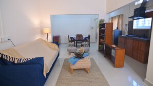 A compact living space with a bed, a dining table with chairs, a kitchenette, and a small seating area. - Rün Lirak, Lovely Home: Tremendous 2-bedroom house with AC in Guwahati (Guwahati)