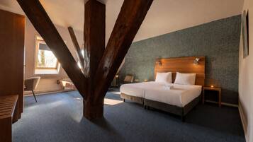 A bedroom with a large bed, a wooden ceiling beam, a nightstand, and a window.