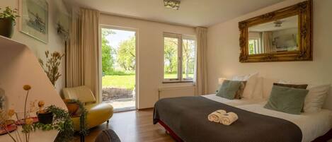 Habitación de hotel con cama, escritorio, silla, ventana grande y espejo.
