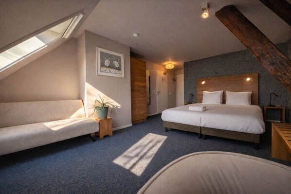 Ein Schlafzimmer mit einem Bett, einer Schlafcouch, einer Zimmerpflanze und einer Deckenleuchte.
