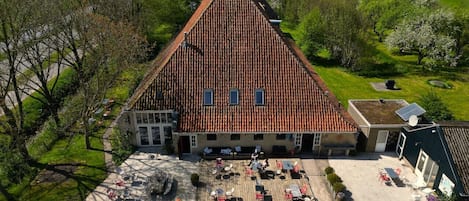 A large building with a steeply pitched roof, a courtyard with outdoor seating, and a flagpole.
