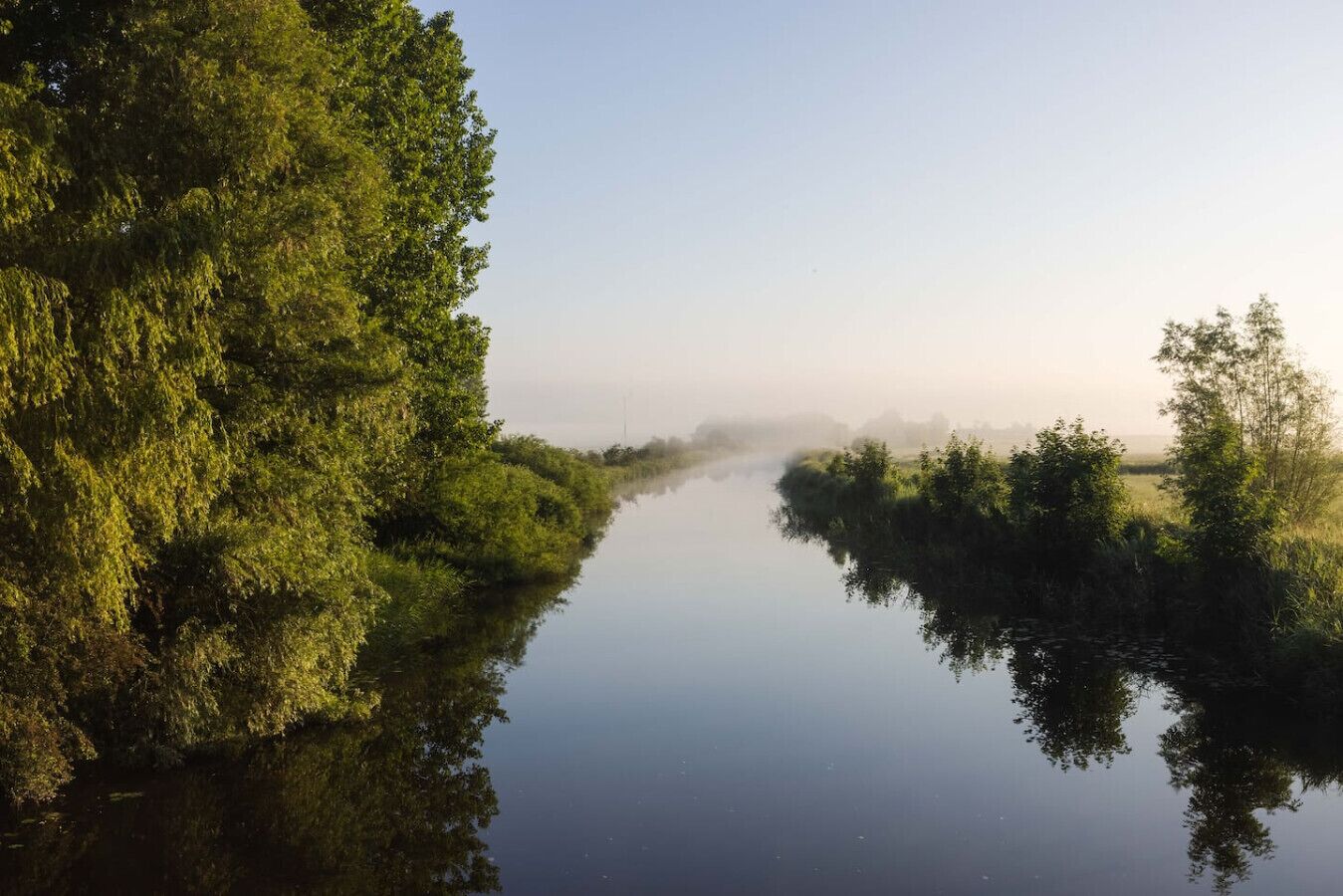 A calm river with dense greenery on both sides.