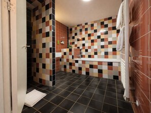 Ein Badezimmer mit Wandfliesen in Schachbrettmuster, einer Badewanne und einer Duschkabine.