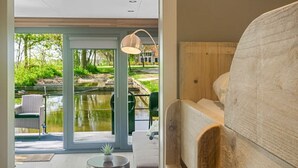 A modern interior with a wooden bench, a round table with a plant, and a view of a garden through glass doors. - Houseboat Doeke Sleat bij Leeuwarden (Weidum)
