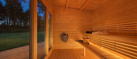 Una sala de sauna con paredes y bancos de madera, un ventanal y vistas al exterior.