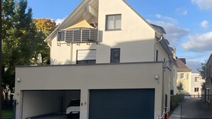 A two-story residential building with a garage, a balcony, and a small window. - Holiday Home 'Fortuna Suite' with Balcony and Wi-Fi (Wiesbaden)