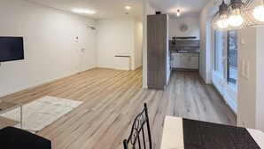A modern kitchen with a window, a dining area with a table and chairs, and a hallway leading to another room. - Holiday Home 'Fortuna Suite' with Balcony and Wi-Fi (Wiesbaden)
