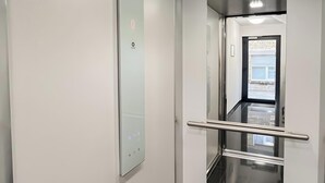 A modern elevator with a control panel, a handrail, and a reflective floor. - Holiday Home 'Fortuna Suite' with Balcony and Wi-Fi (Wiesbaden)