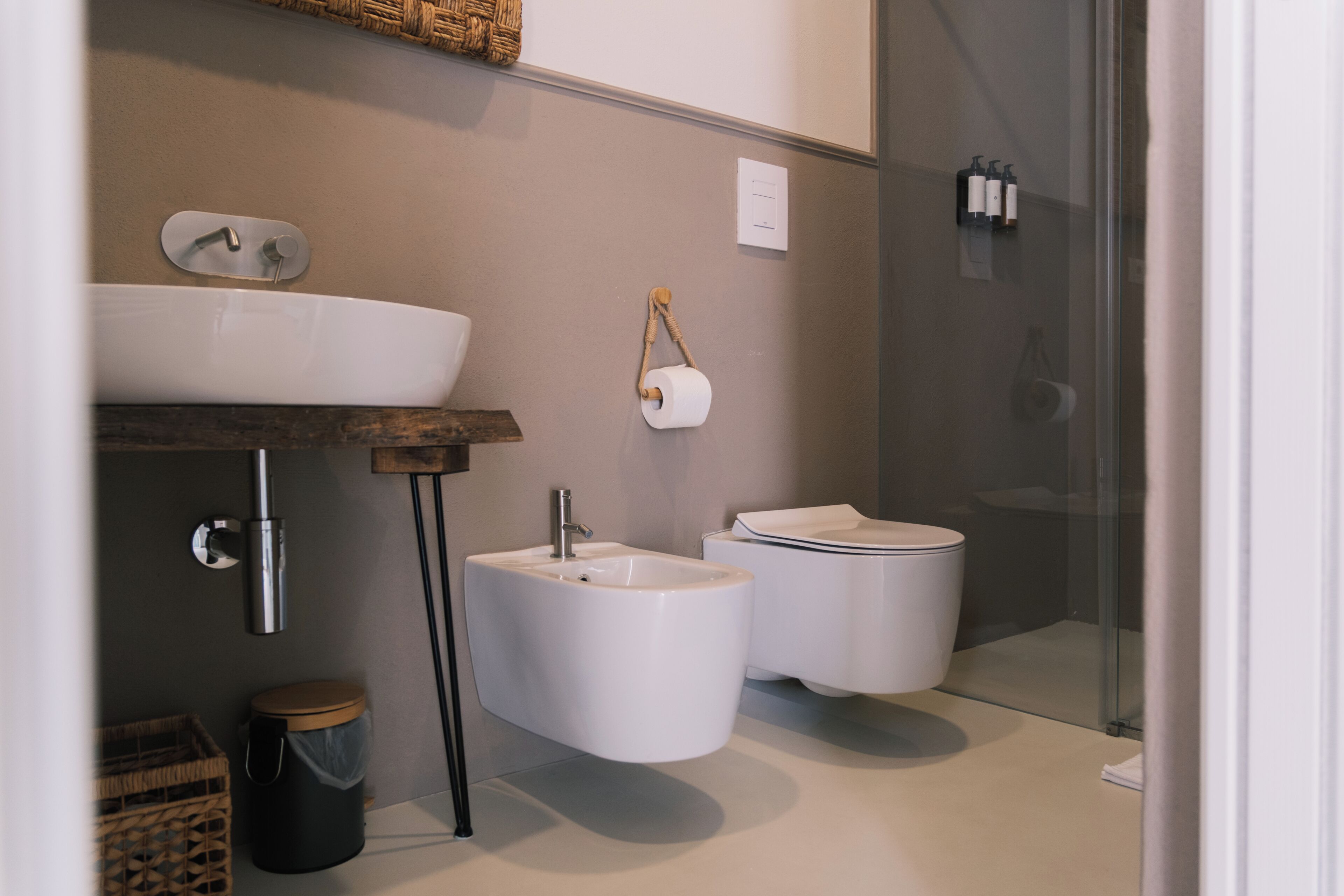 A modern bathroom with a large sink, bidet, toilet, and glass shower enclosure.