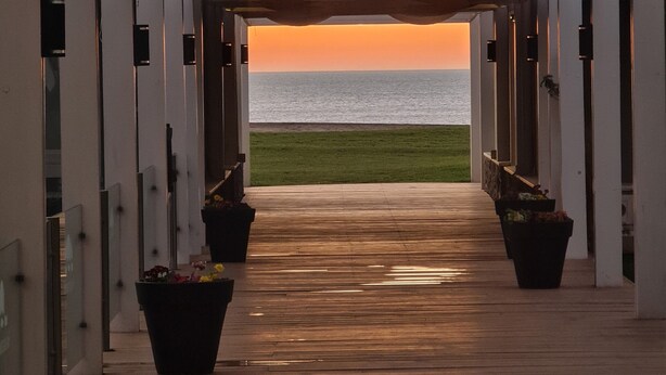 Un couloir menant à une plage offrant une vue sur le coucher de soleil.