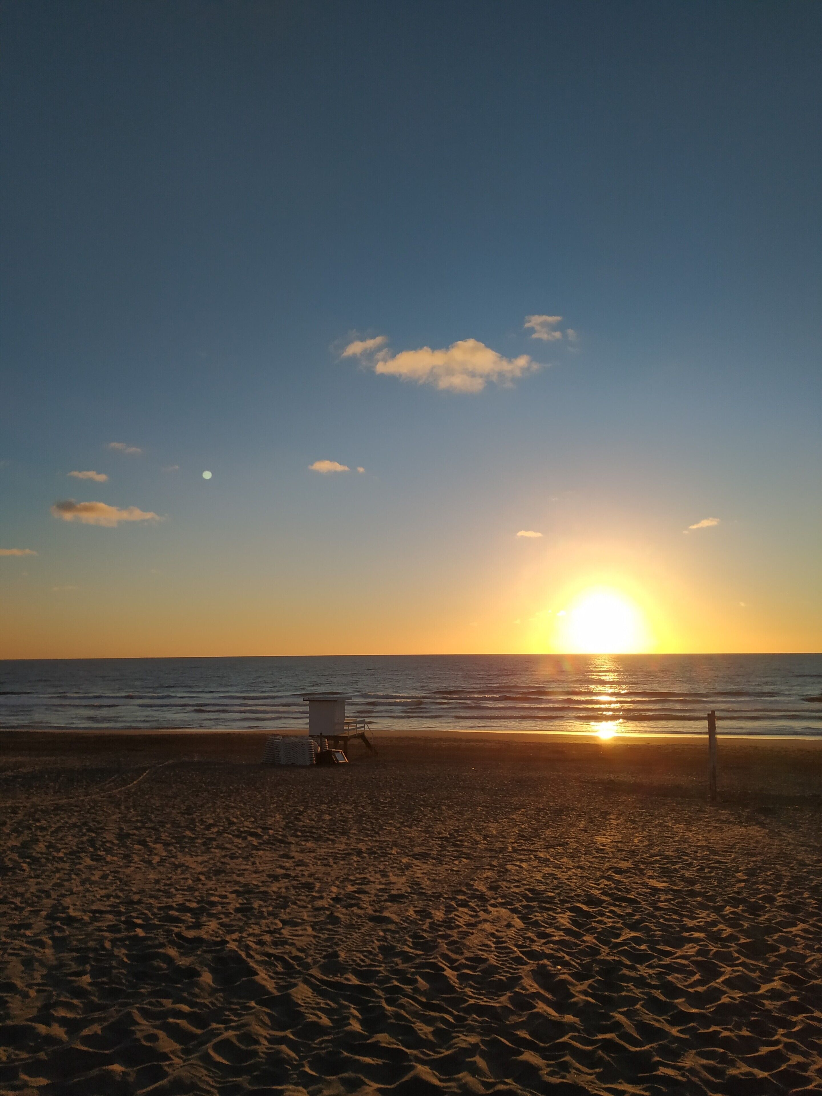A beach with a lifeguard tower and a clear sky.
