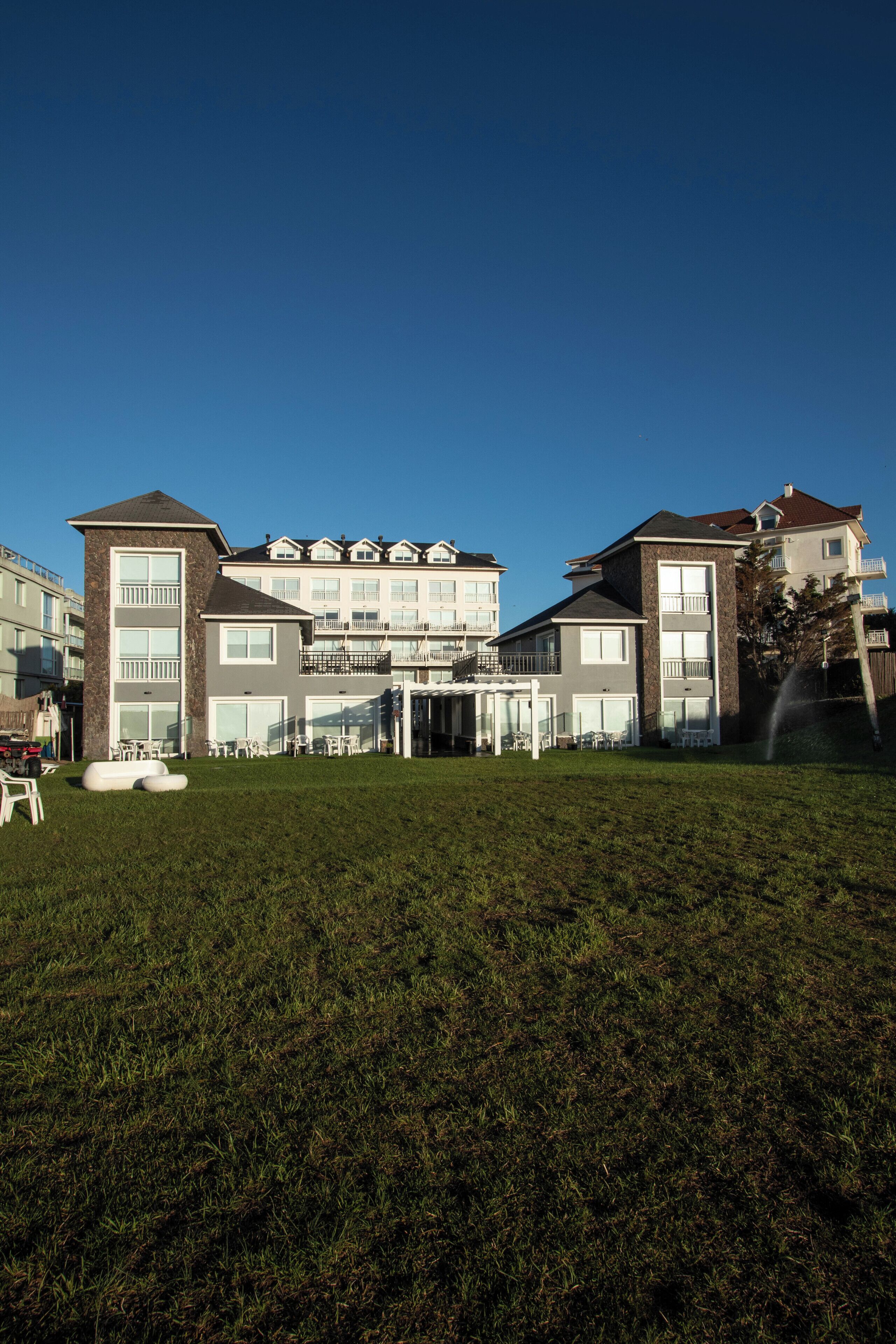Un edificio residencial de varios pisos con un césped bien cuidado y una zona de estar al aire libre.