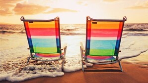 Zwei Strandstühle mit Streifenmuster zum Meer ausgerichtet.