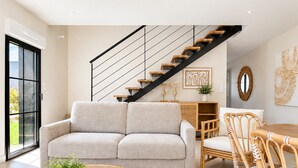 Una sala moderna con sofá, una mesita de centro de mimbre y una escalera.
