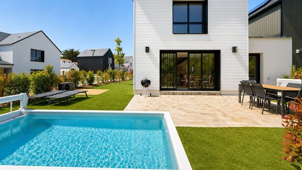 Una casa moderna con piscina, patio y zona de estar al aire libre.