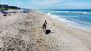 Ein Strand mit Fußabdrücken, Sonnenschirmen und Menschen.