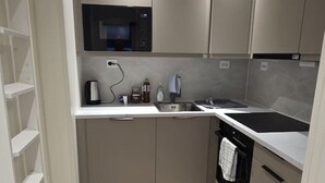 Una cocina compacta con microondas, pileta y alacenas.