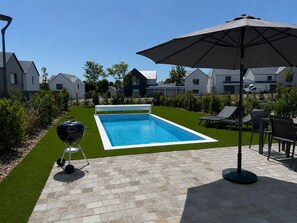 A swimming pool with a surrounding patio area, a barbecue grill, and outdoor seating. - Villa 18 – pool – golf – nature – 6/8 people (Talmont-Saint-Hilaire)
