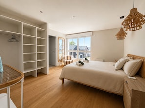 Un dormitorio con una cama grande, un armario, una silla y una mesa.