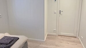 Une chambre à coucher avec un lit, une porte et un interrupteur sur le mur.
