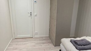 Een slaapkamer met een bed, nachtkastje, kast en een deur.