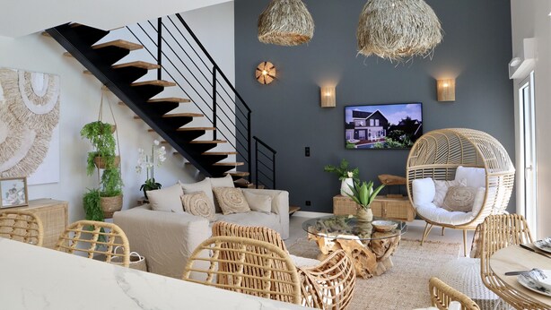 A modern living room with a staircase, wicker furniture, and a flat-screen TV. - Villa 10 – pool – golf – nature – 6/8 people (Talmont-Saint-Hilaire)