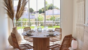 A dining area with a round table, wicker chairs, and a large vase of dried plants. - Villa 10 – pool – golf – nature – 6/8 people (Talmont-Saint-Hilaire)