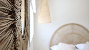 A bedroom with a large bed, a hanging light fixture, and a wall-mounted decorative piece. - Villa 10 – pool – golf – nature – 6/8 people (Talmont-Saint-Hilaire)