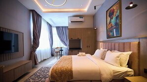 Ein modernes Hotelzimmer mit einem großen Bett, einem Flachbildfernseher, einem Schreibtisch und einem Gemälde an der Wand.