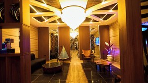 Eine moderne Lobby mit einem zentralen Kronleuchter, Holzvertäfelung und einer Sitzecke mit kleinem Tisch und Stühlen.