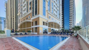 Piscina no terraço com espreguiçadeiras e vista para edifícios altos.